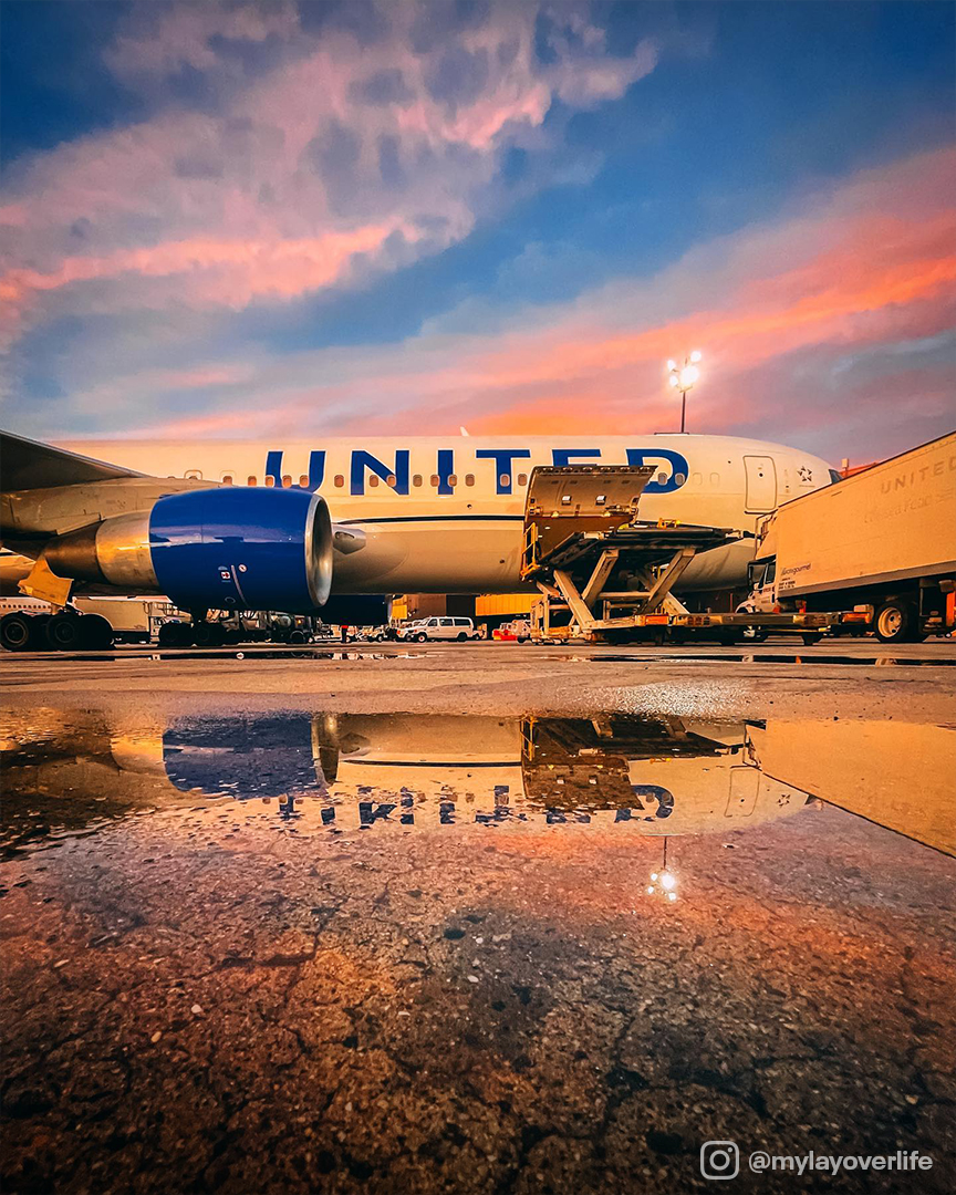 United Airlines avion sur le tarmac au coucher du soleil avec reflet de l'avion dans une flaque.