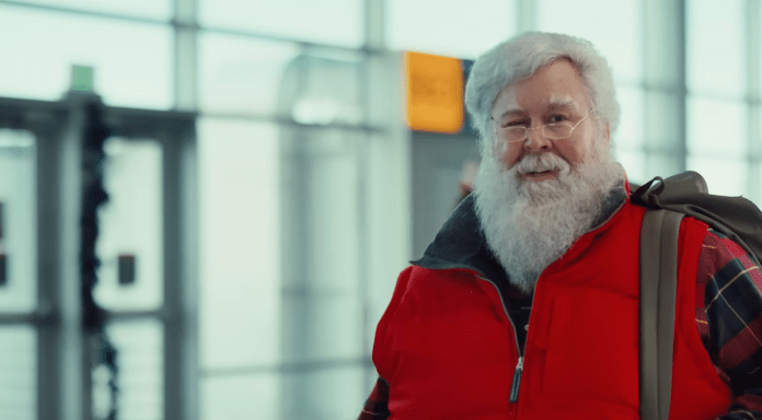 un homme qui ressemble au Père Noël marchant dans un aéroport. 
